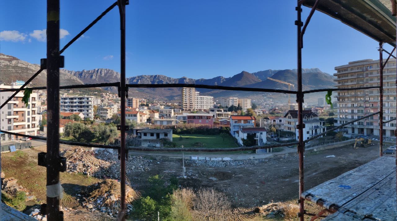 View from the balcony of a house under construction over the city of Bar and the mountains in Montenegro, scaffolding in the foreground.