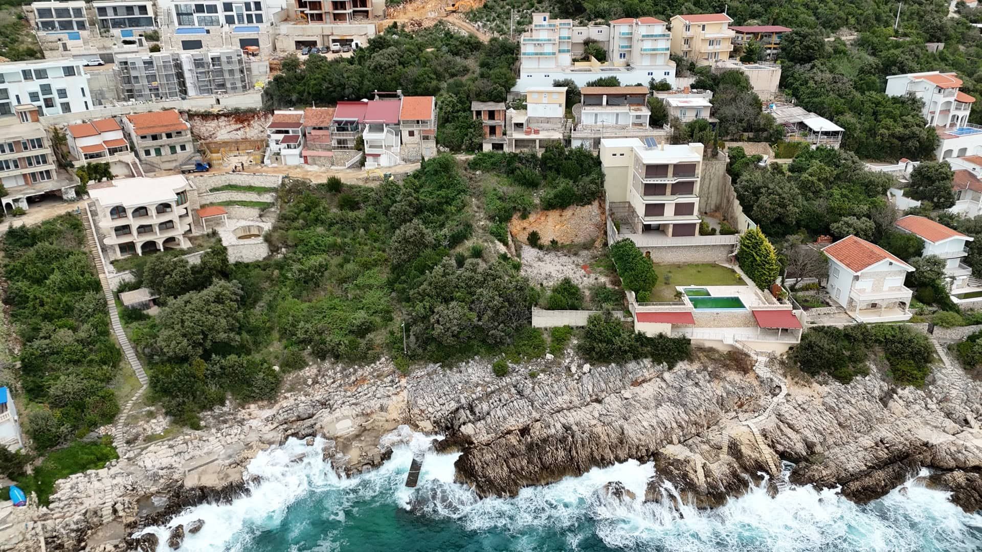 Plot No. 2395 in Utjeha, Montenegro: aerial view of a coastal property with a house and a pool by the sea.