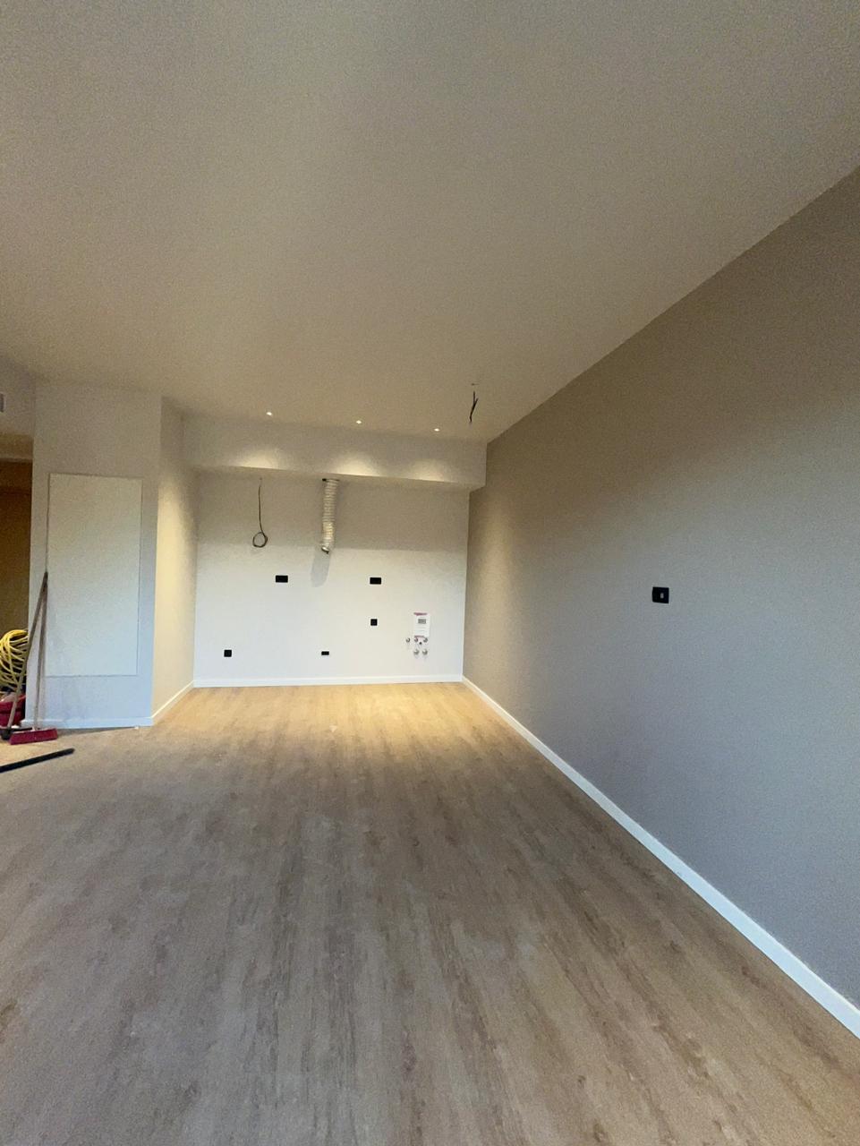 Living room in a new apartment in Tivat, Montenegro: light finishes, laminate flooring, recessed lighting, and utility connections for appliances.