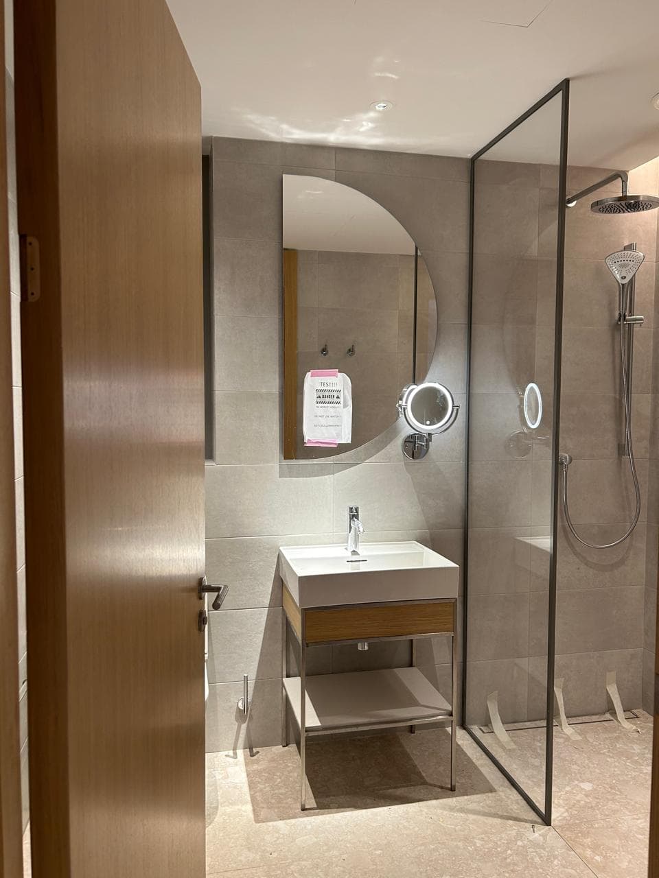 Modern bathroom in an apartment in Tivat, Montenegro: shower cabin, stylish sink, and backlit mirror.