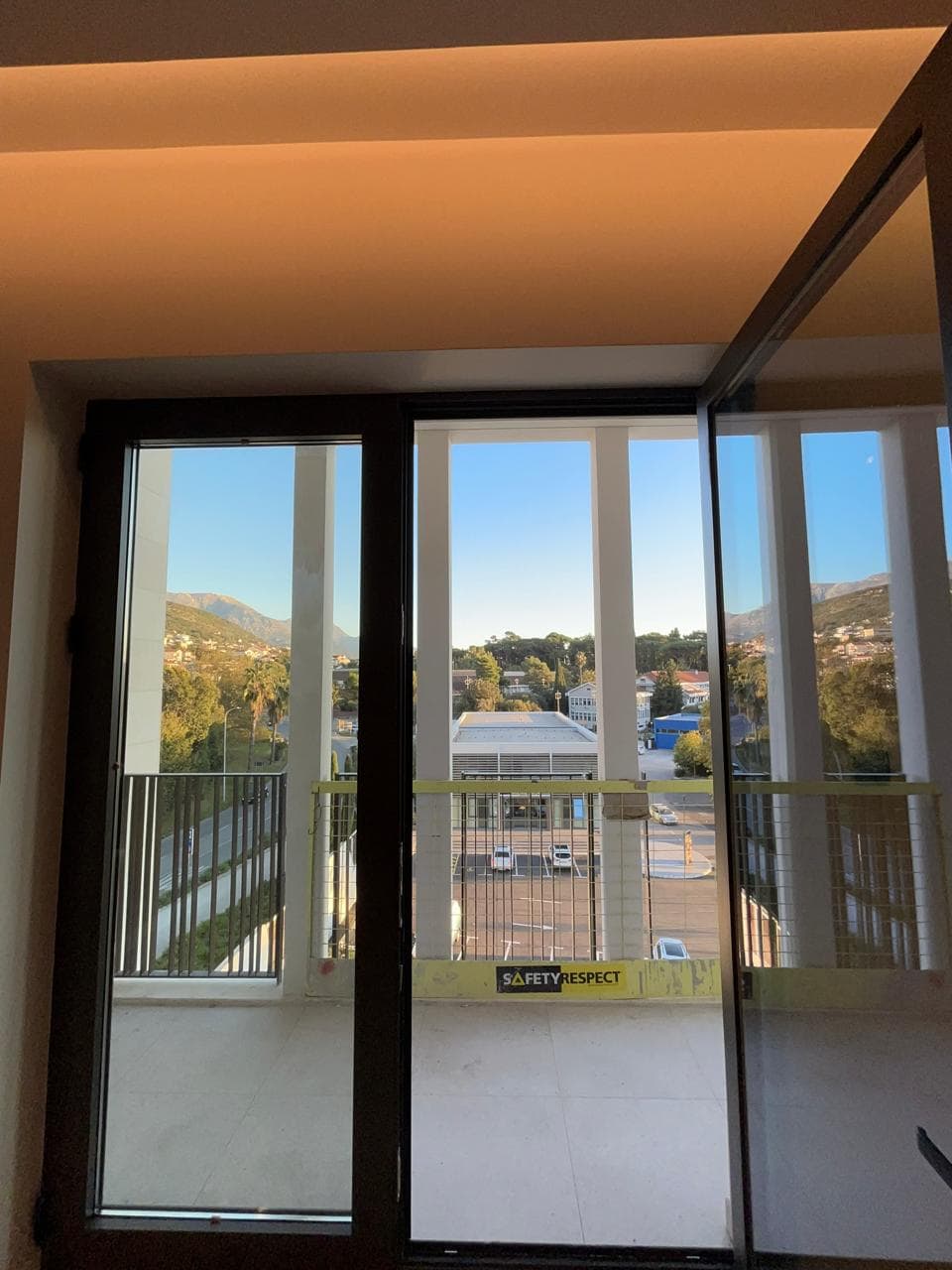 View from the balcony of a new apartment in Tivat, Montenegro: panoramic windows, modern finishes, and a mountain landscape.
