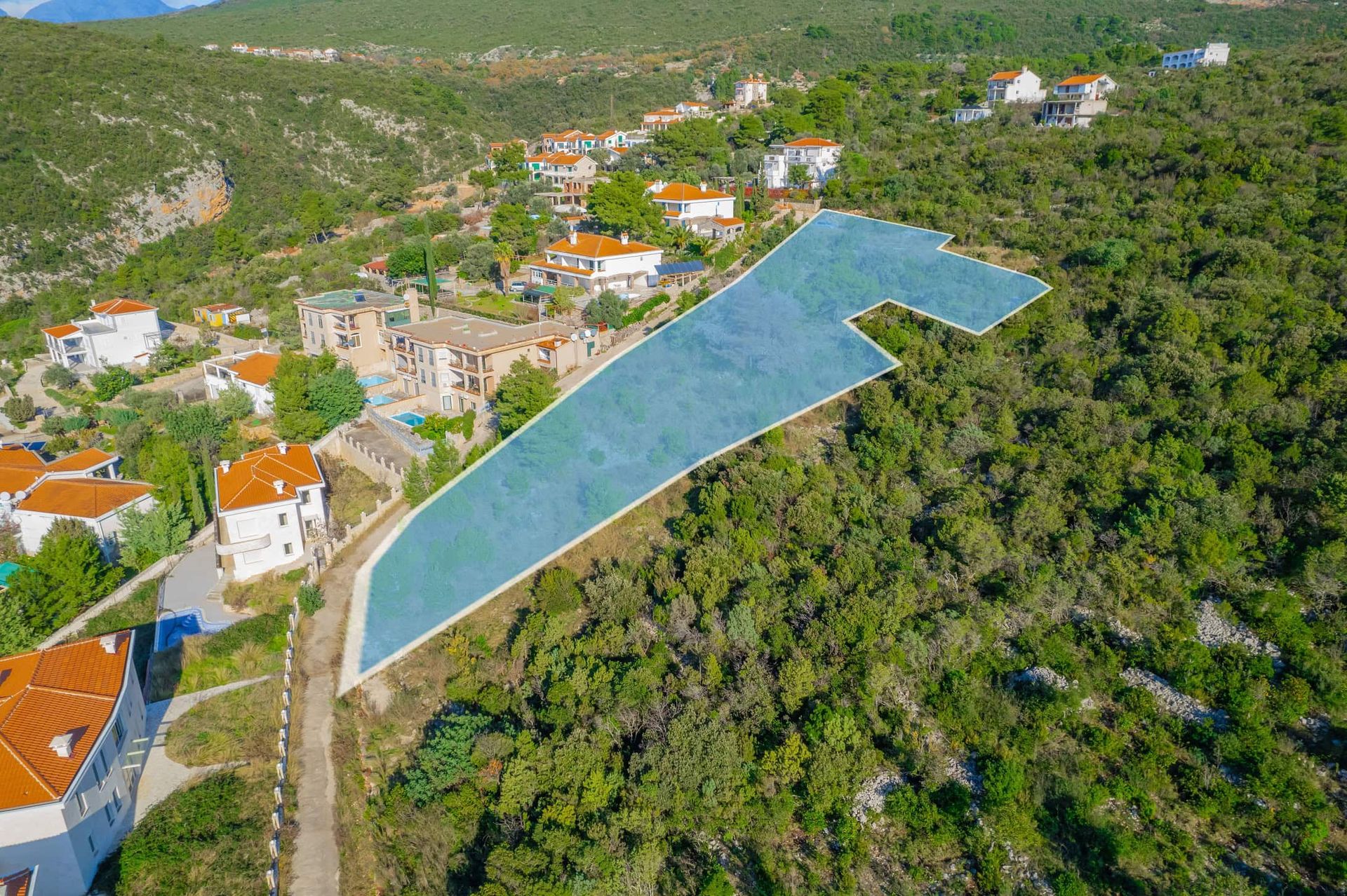 Building plot No. 2390 in Žanjice, Montenegro: aerial view of the land situated among hills and villas.
