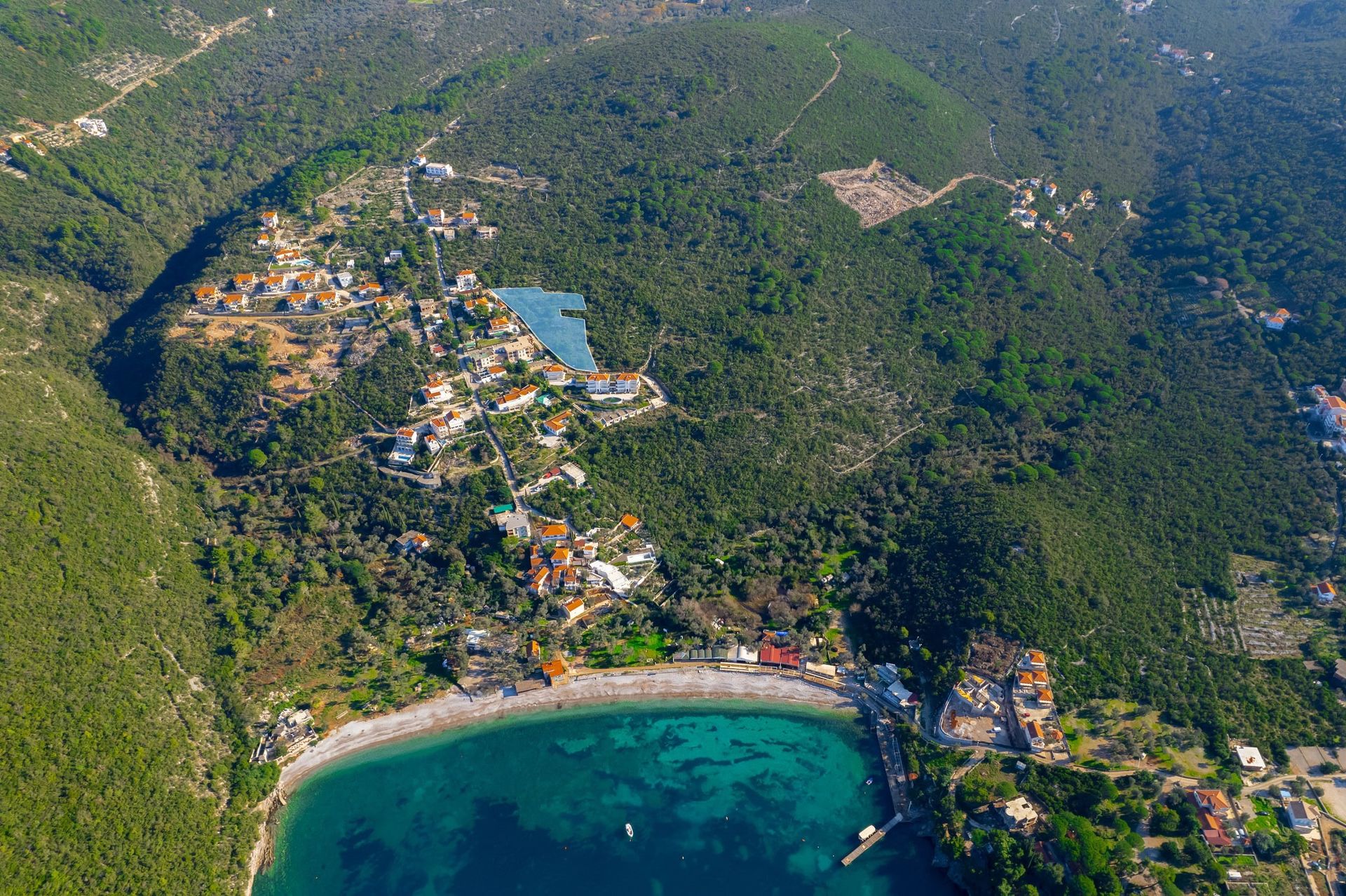Plot of land #2390 in Žanjice, Montenegro: aerial view of the seaside plot surrounded by forests and villas.