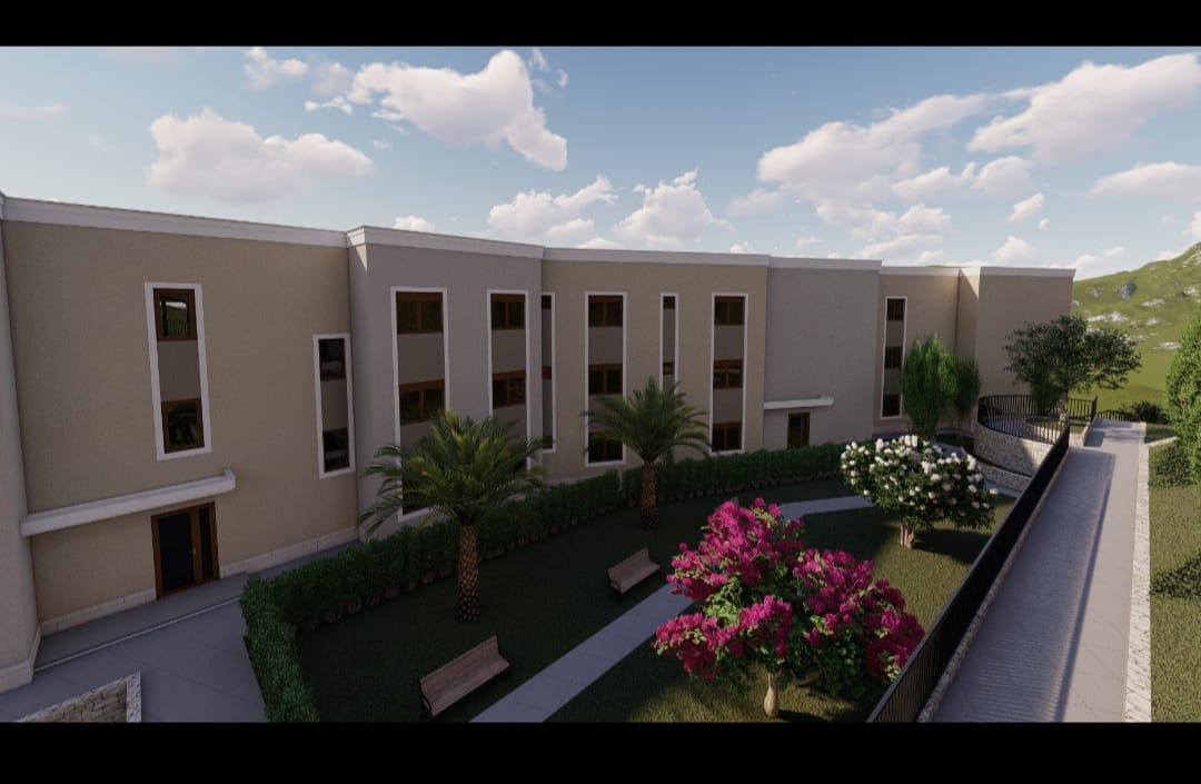 View of a modern residential complex in Budva, Montenegro, with landscaped grounds, palm trees, and walking areas.