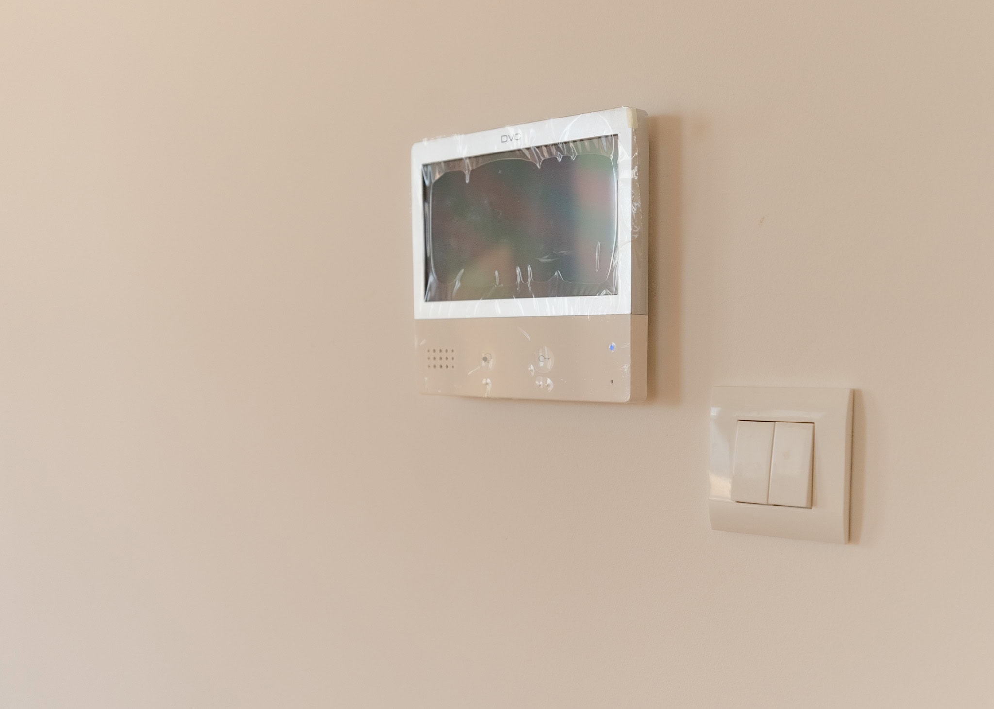 DVC video intercom and a light switch on a light wall in a new apartment in Budva, Montenegro. Modern home features.