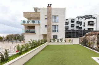 Rooftop terrace with artificial grass overlooking a modern residential building complex.