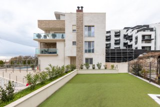 Modern villa in Bečići, Montenegro: facade with terraces, panoramic windows, and a well-maintained green lawn.