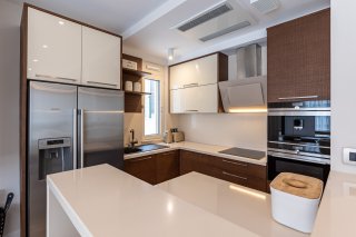 Modern kitchen in a villa in Becici, Montenegro: built-in appliances, glossy cabinets, and a light-colored countertop.