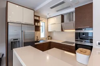Modern kitchen featuring wood cabinetry, stainless steel appliances, and white countertops.