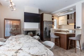 Modern open-plan kitchen and living room featuring a marble table, fireplace, and breakfast bar in a villa in Bečići, Montenegro.
