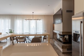 Modern open-plan kitchen and living room with a fireplace and dining area in a villa in Bečići, Montenegro. Interior with premium finishes.