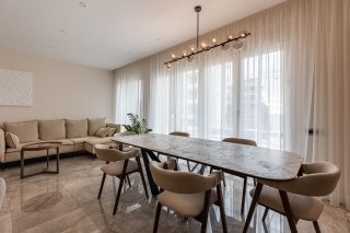 Modern living room with a dining area in a villa in Bečići, Montenegro: marble flooring, designer table, and light-colored furniture.