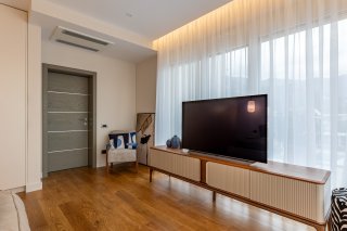 Modern living room with a TV area in a villa, Becici, Montenegro: parquet flooring, designer furniture, and panoramic windows.