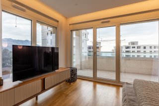 Modern living room with floor-to-ceiling windows and terrace access in a villa, Becici, Montenegro.