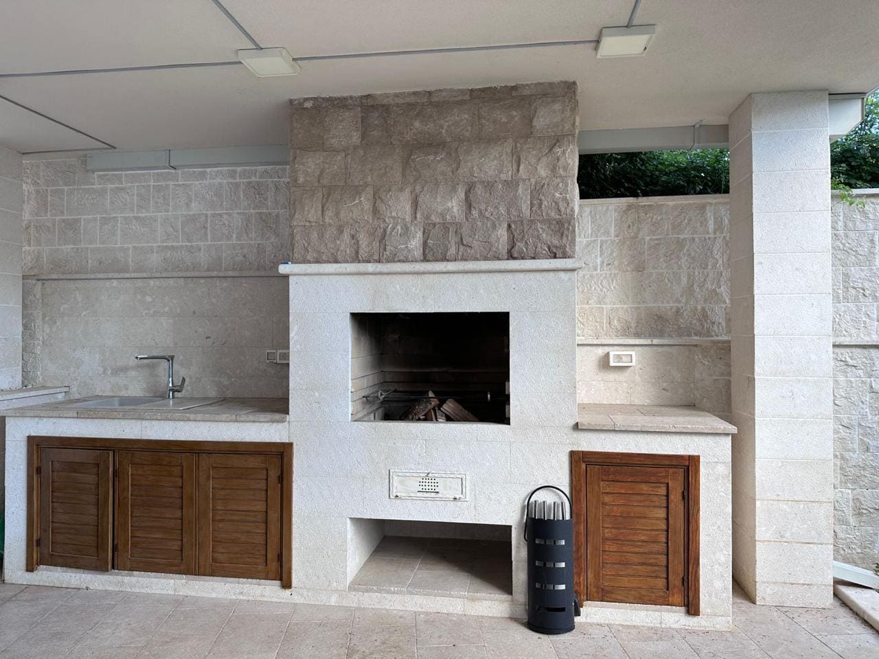 Summer kitchen with a stone barbecue and sink on a villa terrace in Bečići, Montenegro. Natural stone finish.