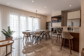 Modern living room with a dining area and kitchen in a villa in Becici, Montenegro: marble flooring, stylish furniture.