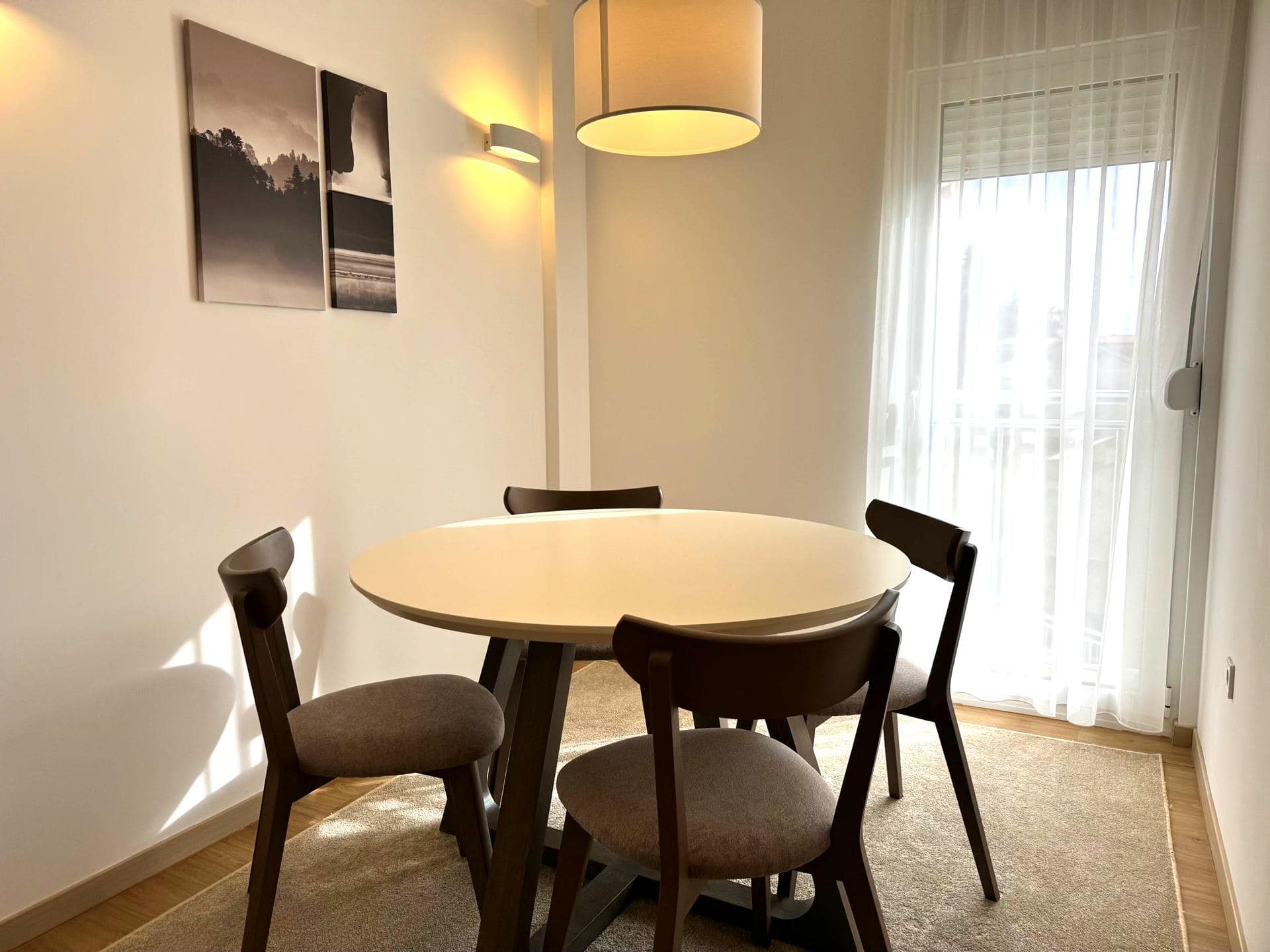 Dining area in an apartment in Tivat, Montenegro: round table, upholstered chairs, and modern lighting.