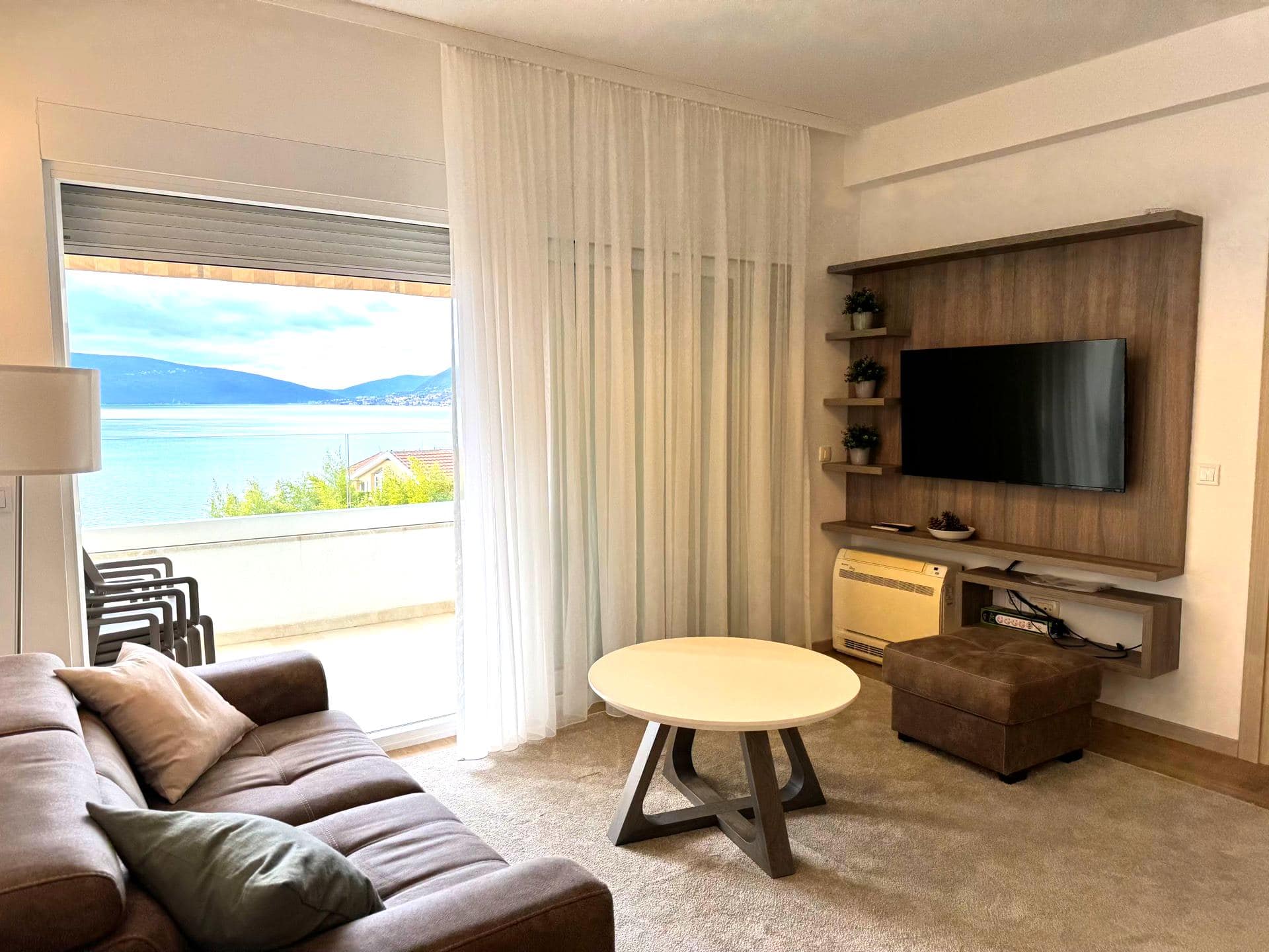 Living room in an apartment in Tivat, Montenegro: sea view, modern furniture, TV area, and access to the terrace.
