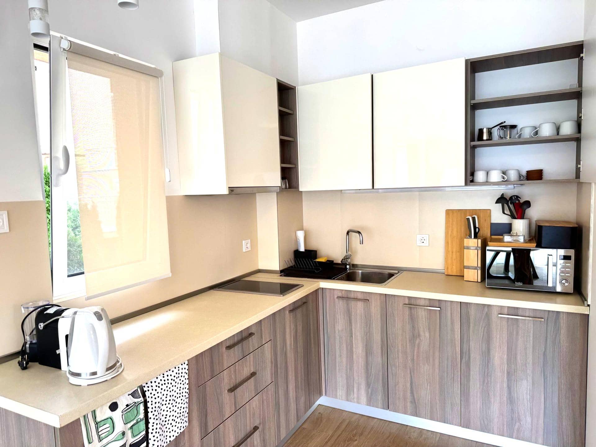 Modern corner kitchen in an apartment in Tivat, Montenegro: light fronts, built-in appliances, and a dining area.