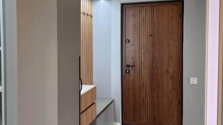 Modern hallway in an apartment in Tivat, Montenegro: a stylish wood-look front door and slatted wall paneling.