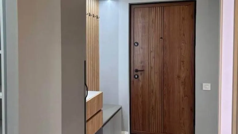 Entryway featuring a wooden door, floating console table, and wall-mounted coat rack panel.