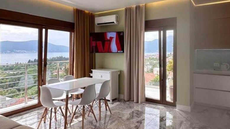 Living room with panoramic sea view in an apartment in Tivat, Montenegro: modern furniture, marble floor, and terrace.