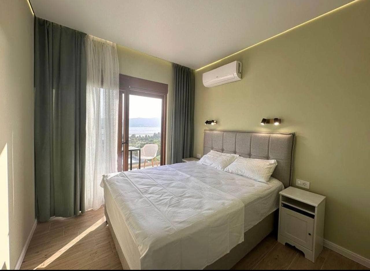 Modern bedroom in an apartment in Tivat, Montenegro: double bed, panoramic sea view, and balcony.