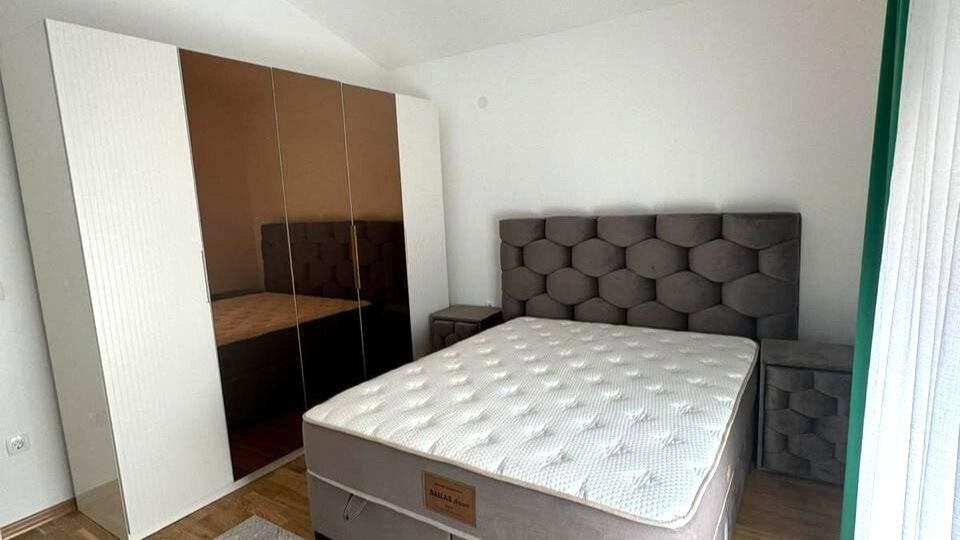 Bedroom in an apartment in Tivat, Montenegro: a double bed with a padded headboard and a wardrobe with mirrored fronts.