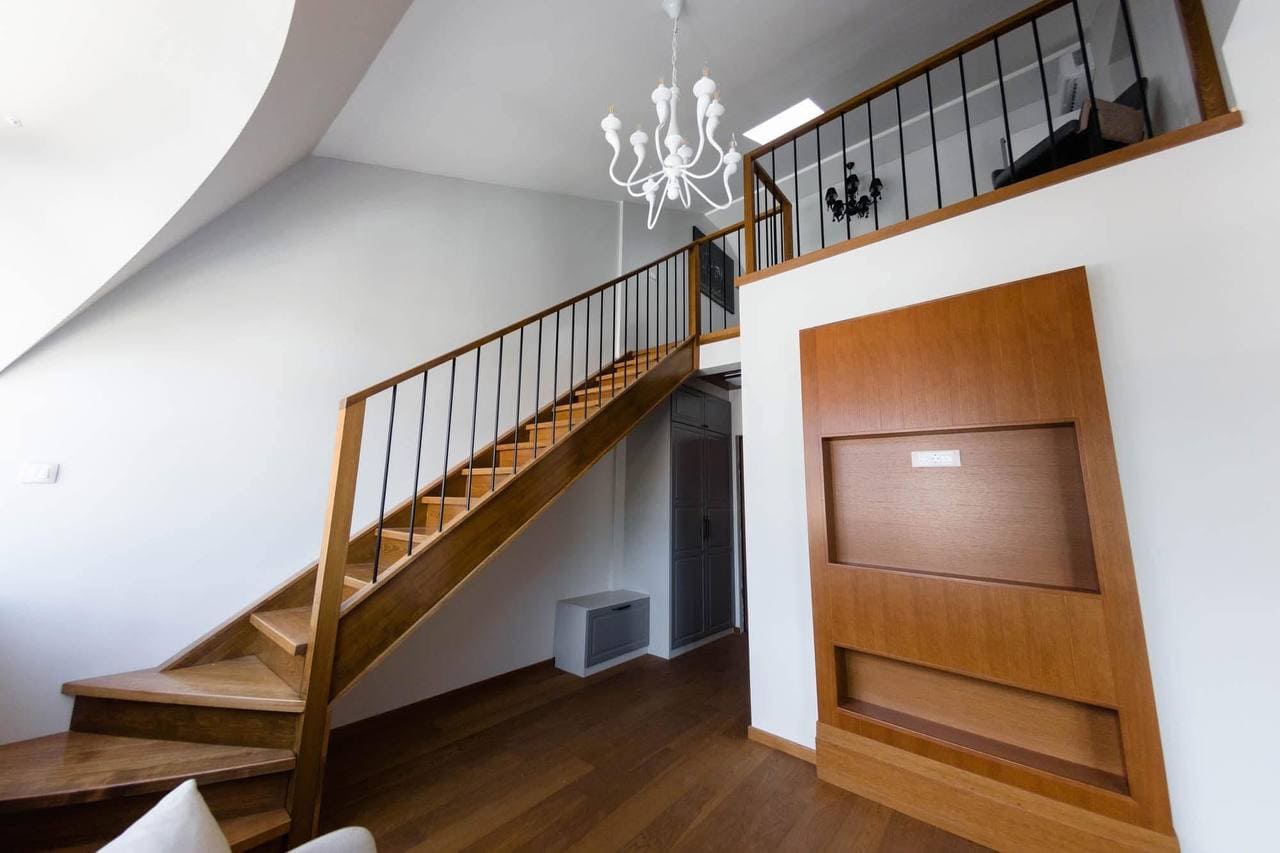 Two-level living room with a wooden staircase in a modern apartment in Tivat, Montenegro.