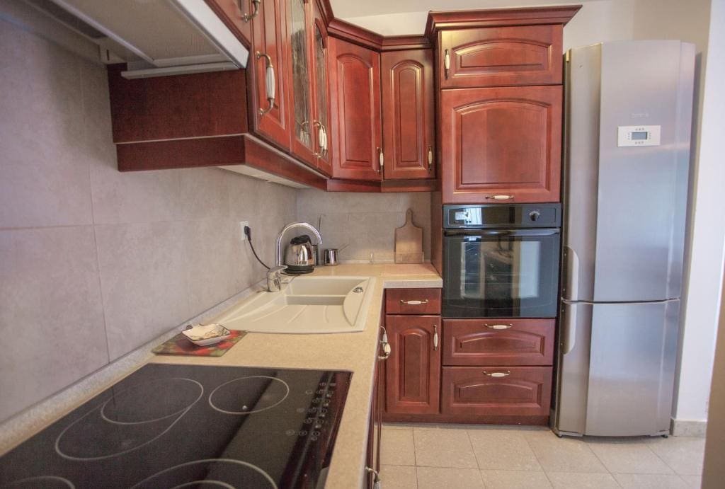 Kitchen in an apartment in Budva, Montenegro: a classic dark wood kitchen set, built-in appliances, and a stove.