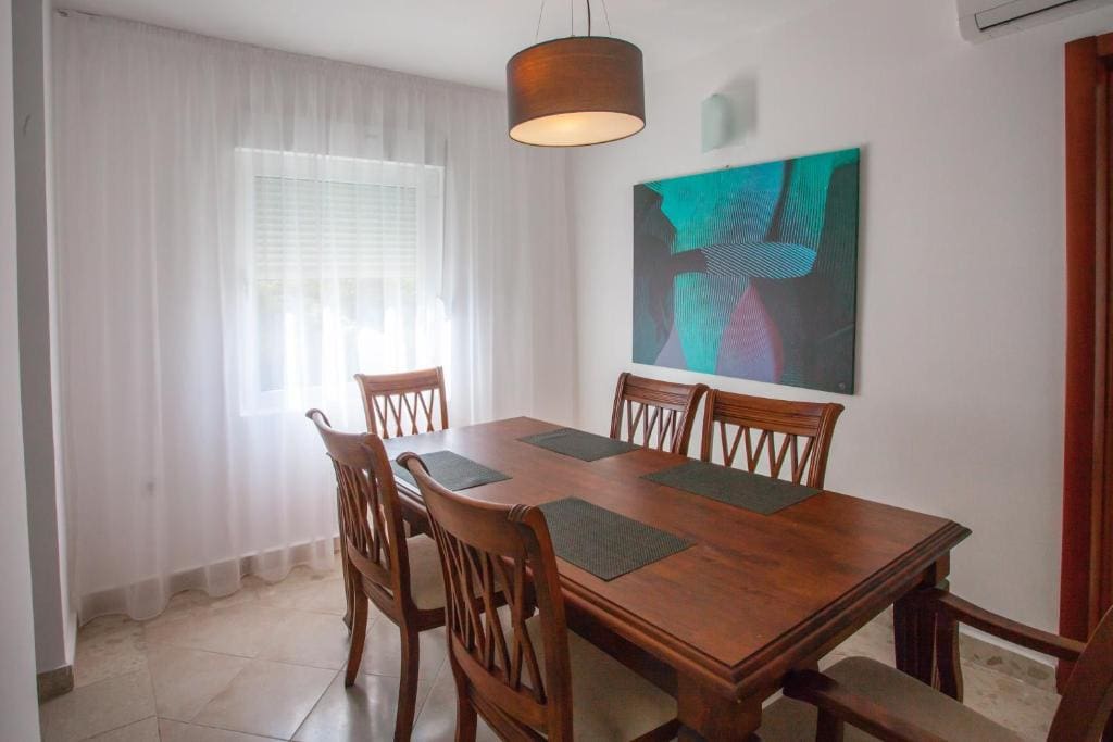 Dining area in an apartment in Budva, Montenegro: a wooden table with chairs, a modern painting, and a bright interior.