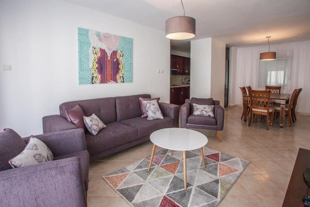 Living room with purple upholstered furniture and a dining area in an apartment in Budva, Montenegro. Modern interior.