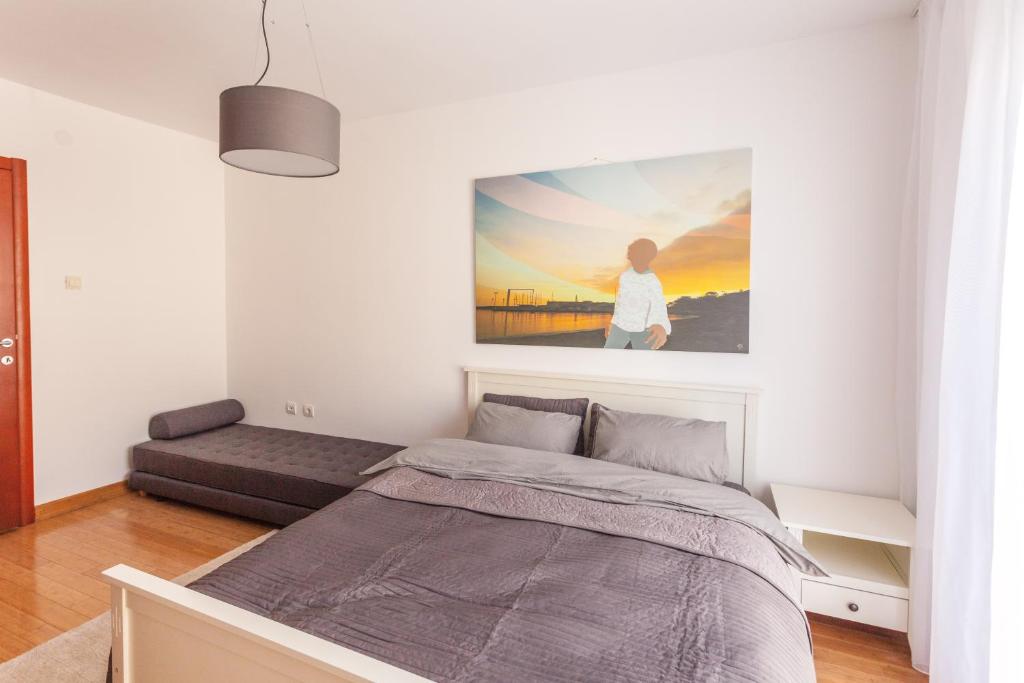 Bright bedroom with a double bed and sofa in an apartment in Budva, Montenegro, modern interior with a painting.