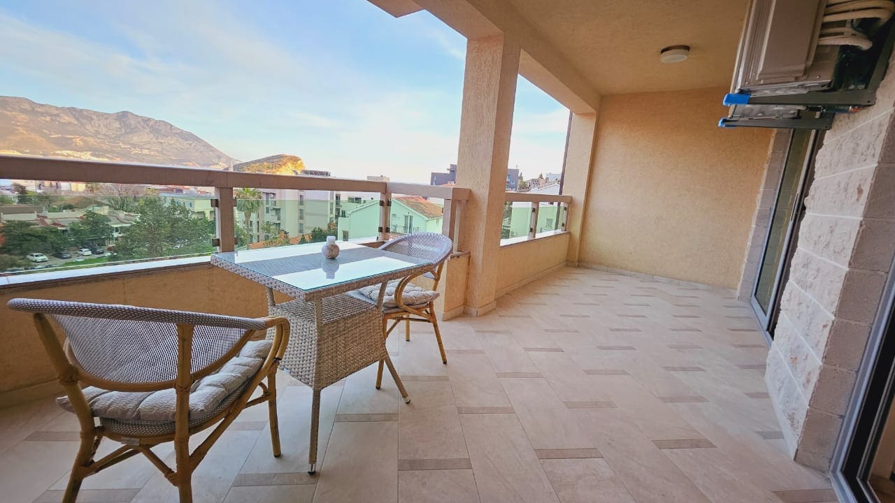 Spacious balcony with wicker furniture and mountain views in an apartment, Budva, Montenegro.