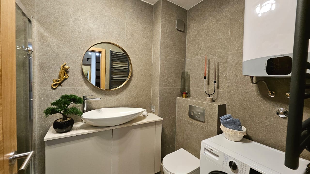 Modern bathroom in an apartment in Budva, Montenegro: stylish finishes, a countertop sink, and a washing machine.