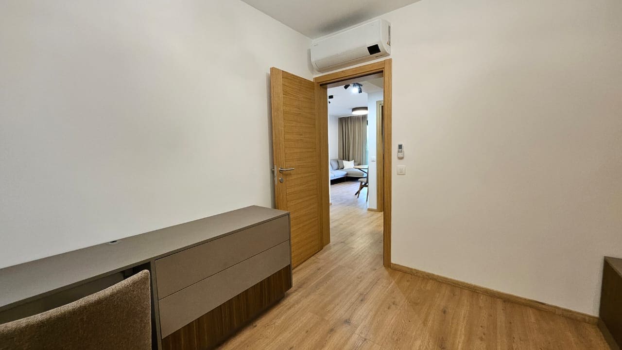 Modern bedroom with a dresser and air conditioner in an apartment for sale, Budva, Montenegro. View of the living room through the door.