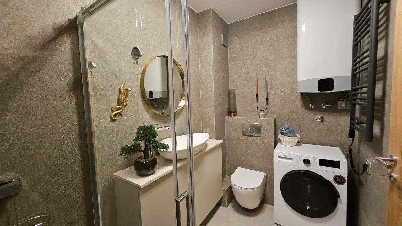 Modern bathroom in an apartment in Budva, Montenegro: shower cabin, washing machine, and stylish finishes.