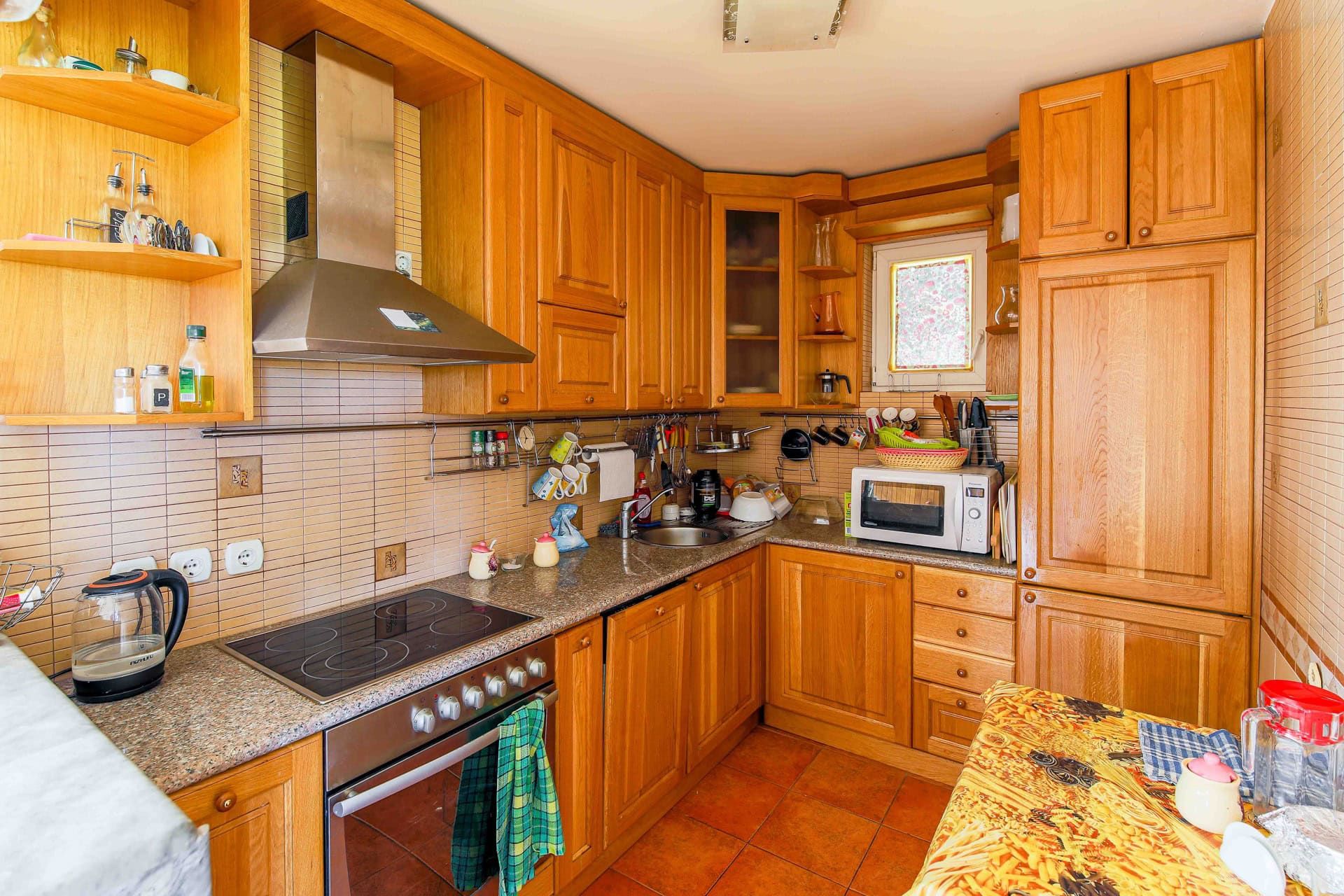 Cozy kitchen with wooden cabinetry and built-in appliances in a house for sale, Utjeha, Montenegro.