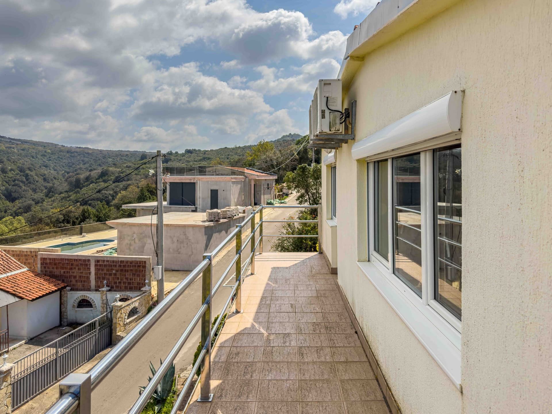 Open balcony with tile flooring and metal railing in a building, Uteha, Montenegro, mountain and street view.