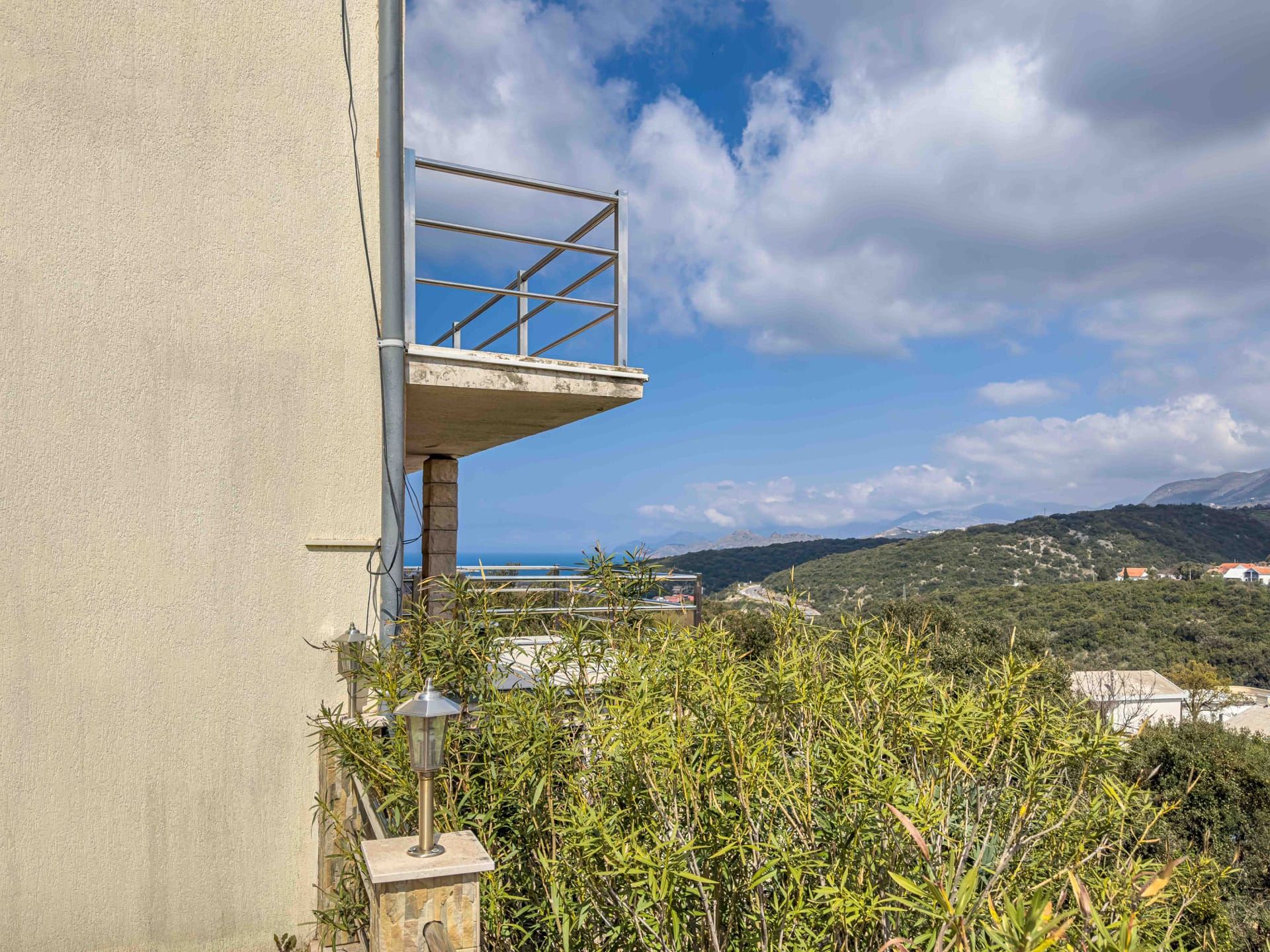 Balcony with a metal railing in a house in Utjeha, Montenegro, with panoramic views of the sea, mountains, and greenery.
