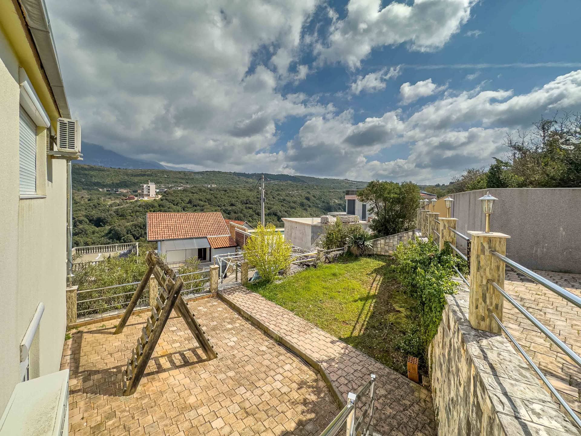 Terrace with a playground and mountain view by the house in Uteha, Montenegro: paved area, garden, and panoramic scenery.