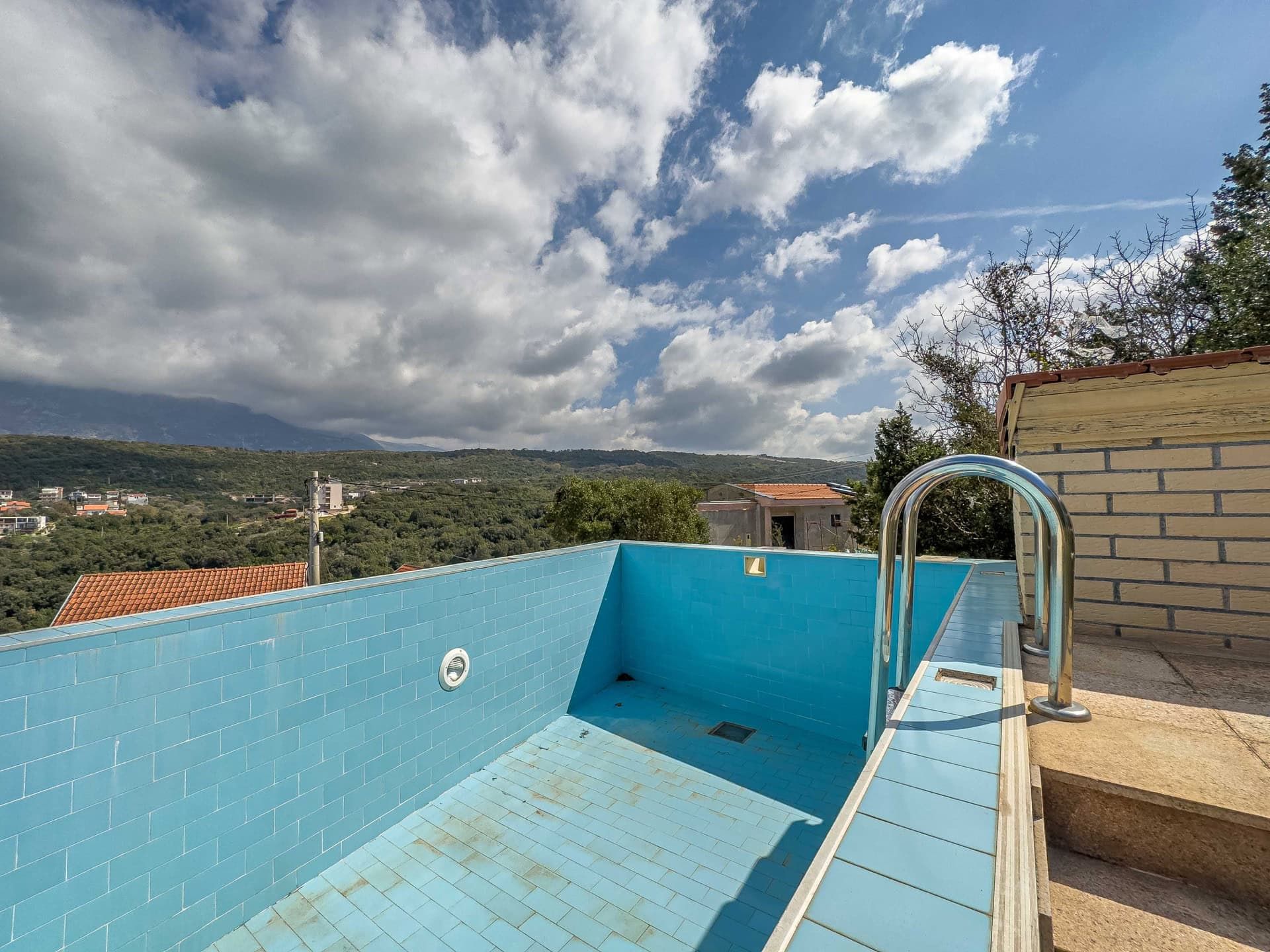 An outdoor pool with blue tiles and mountain views at a house in Utjeha, Montenegro.