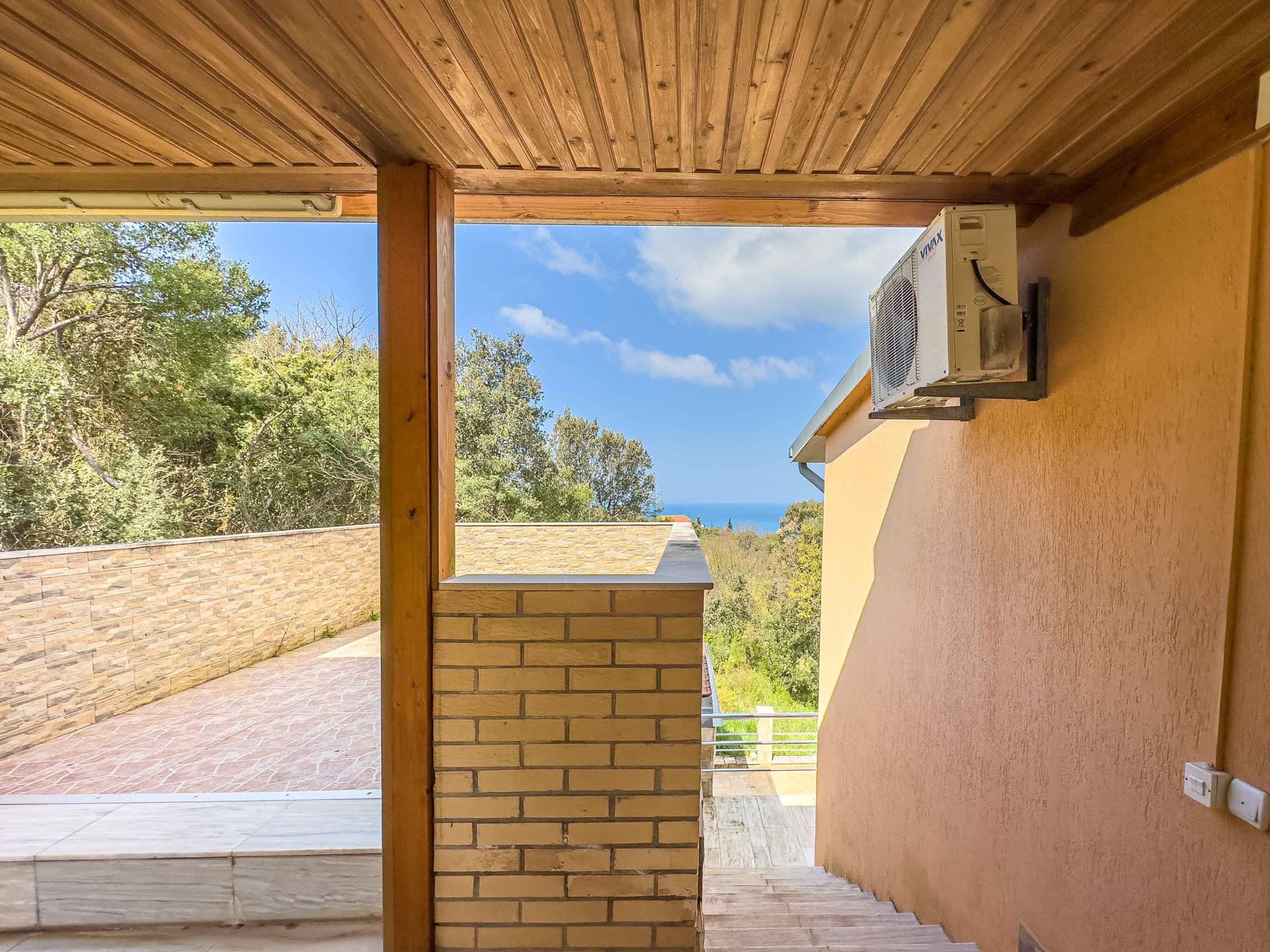 Terrace with sea view in a house, Uteha, Montenegro: wooden ceiling, brick finish, and staircase.