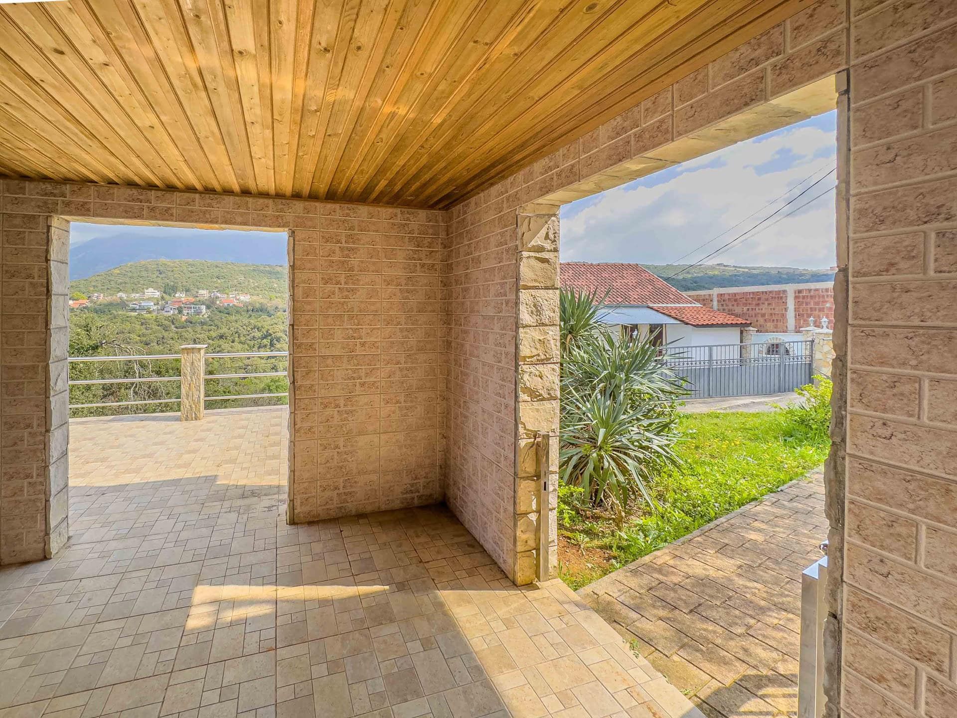 Covered terrace with stone finishes and a wooden ceiling in the house, Utjeha, Montenegro, mountain and garden view.