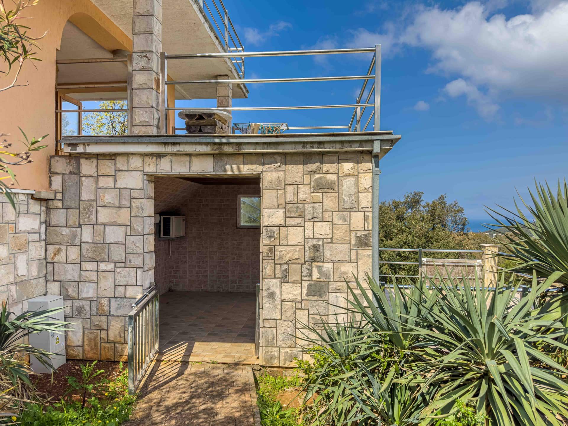 Stone house in Utjeha, Montenegro: terrace with sea view, natural stone cladding, and green grounds.