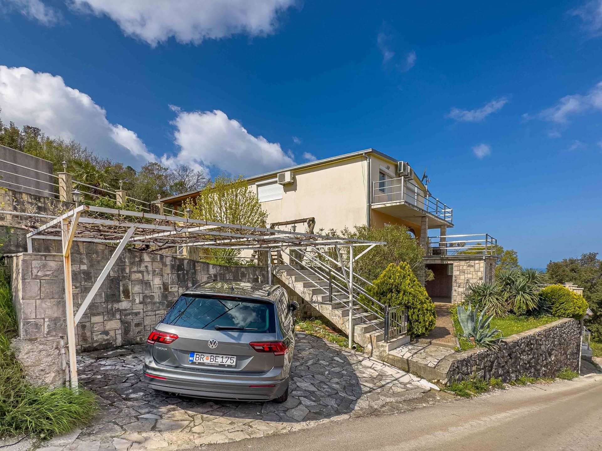 Two-story house in Utjeha, Montenegro: private covered parking, stone facade finish, and terraces with a view.