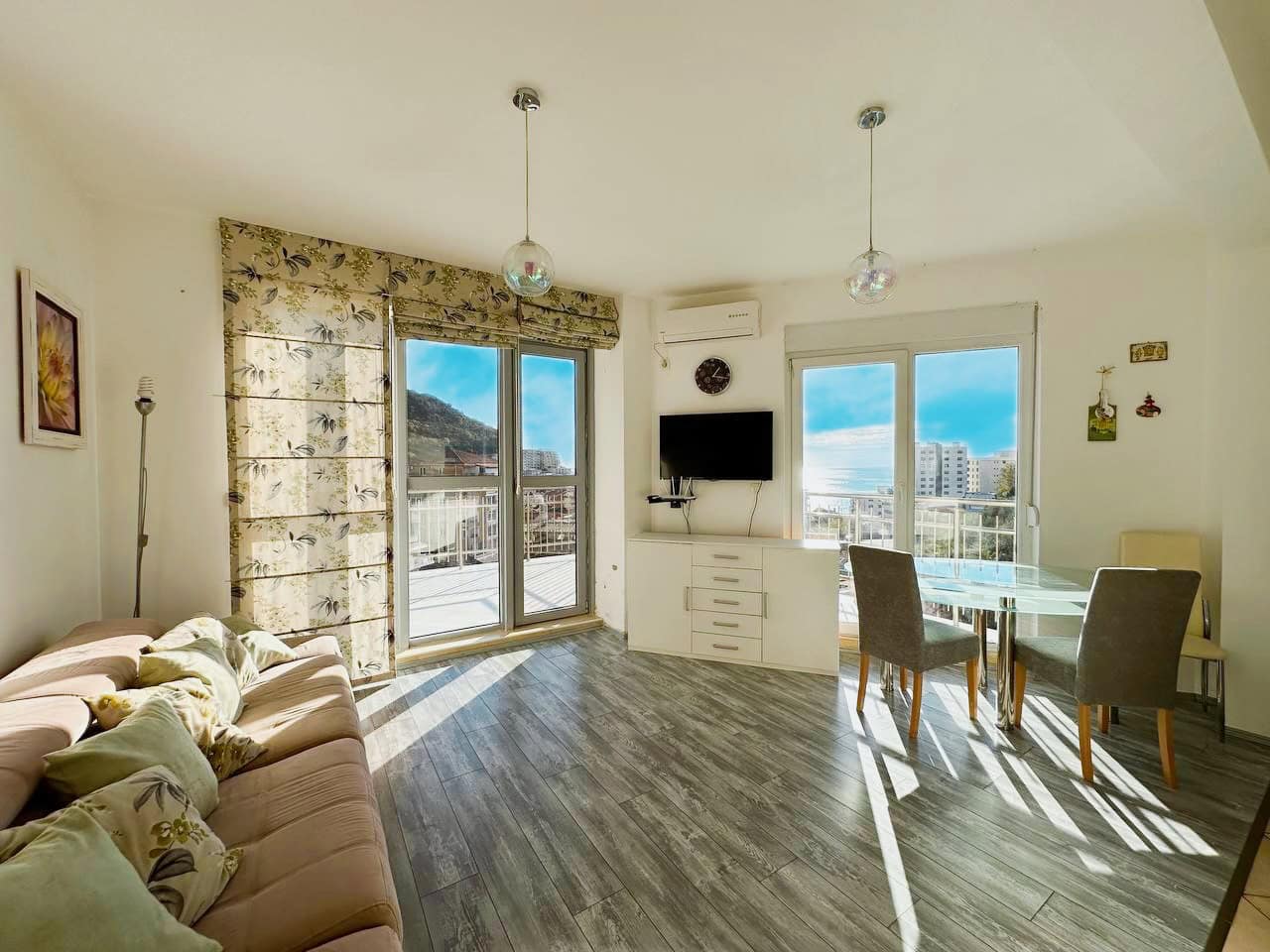 Bright living room with panoramic windows and sea view in an apartment, Becici, Montenegro. Modern furniture and finishes.