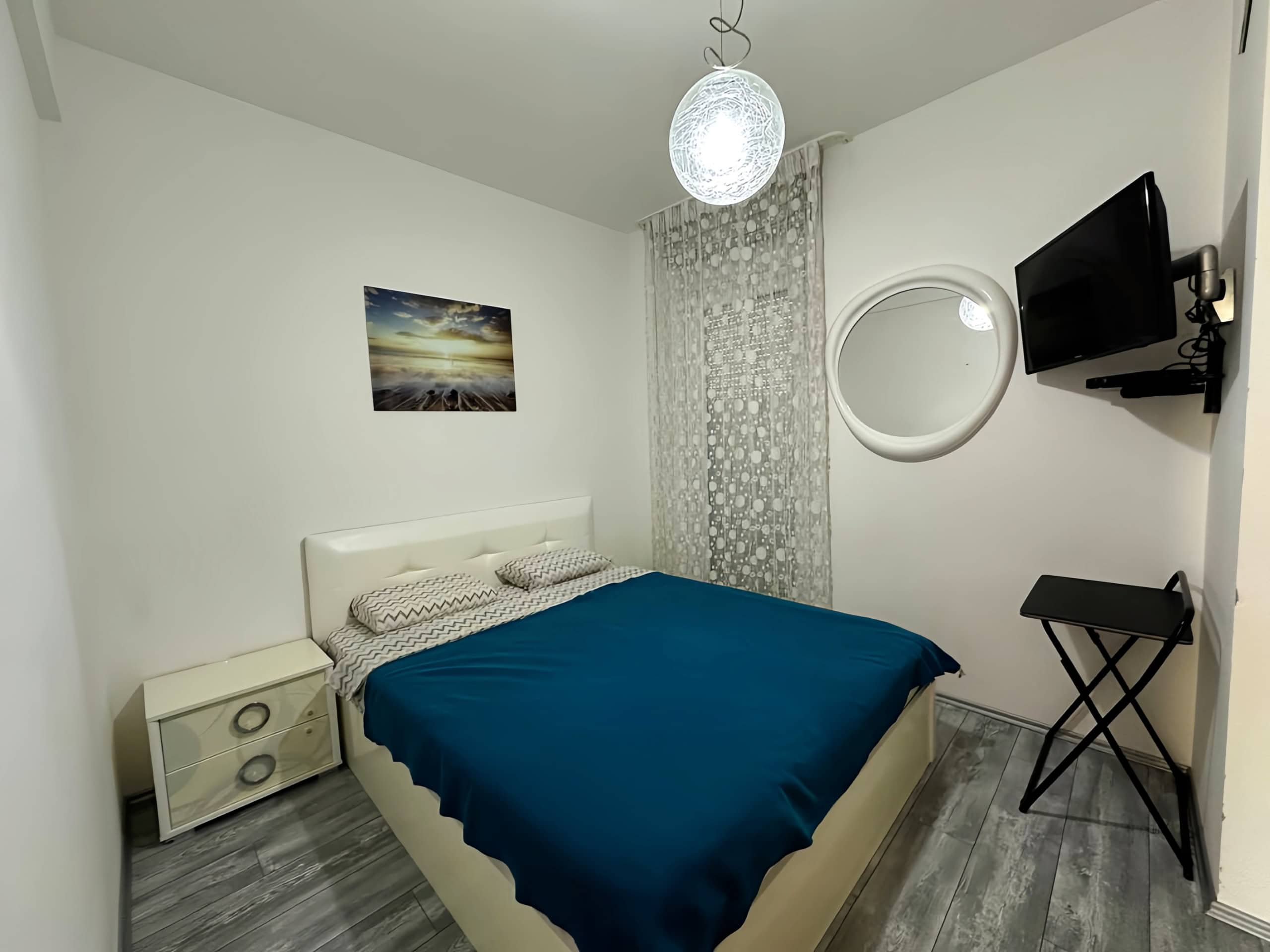 Cozy bedroom with a double bed in an apartment in Bečići, Montenegro: bright interior, TV, and stylish finishes.