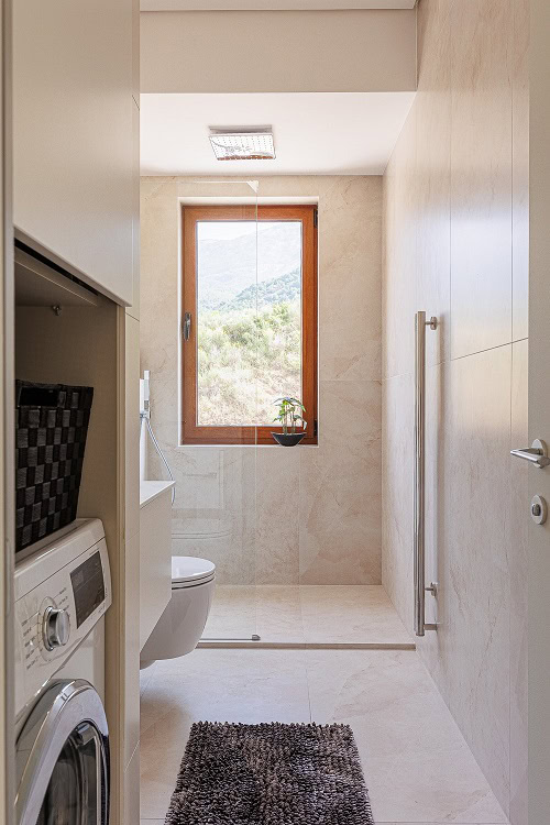 Modern bathroom in an apartment in Bečići, Montenegro: walk-in shower, washing machine, and mountain view.
