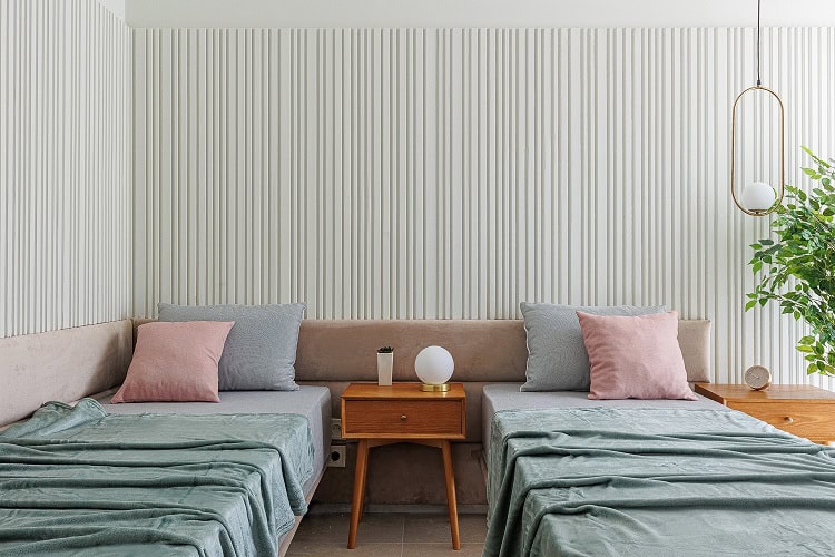Bedroom in an apartment in Bečići, Montenegro: two beds, wooden nightstands, slatted wall paneling, and stylish interior decor.